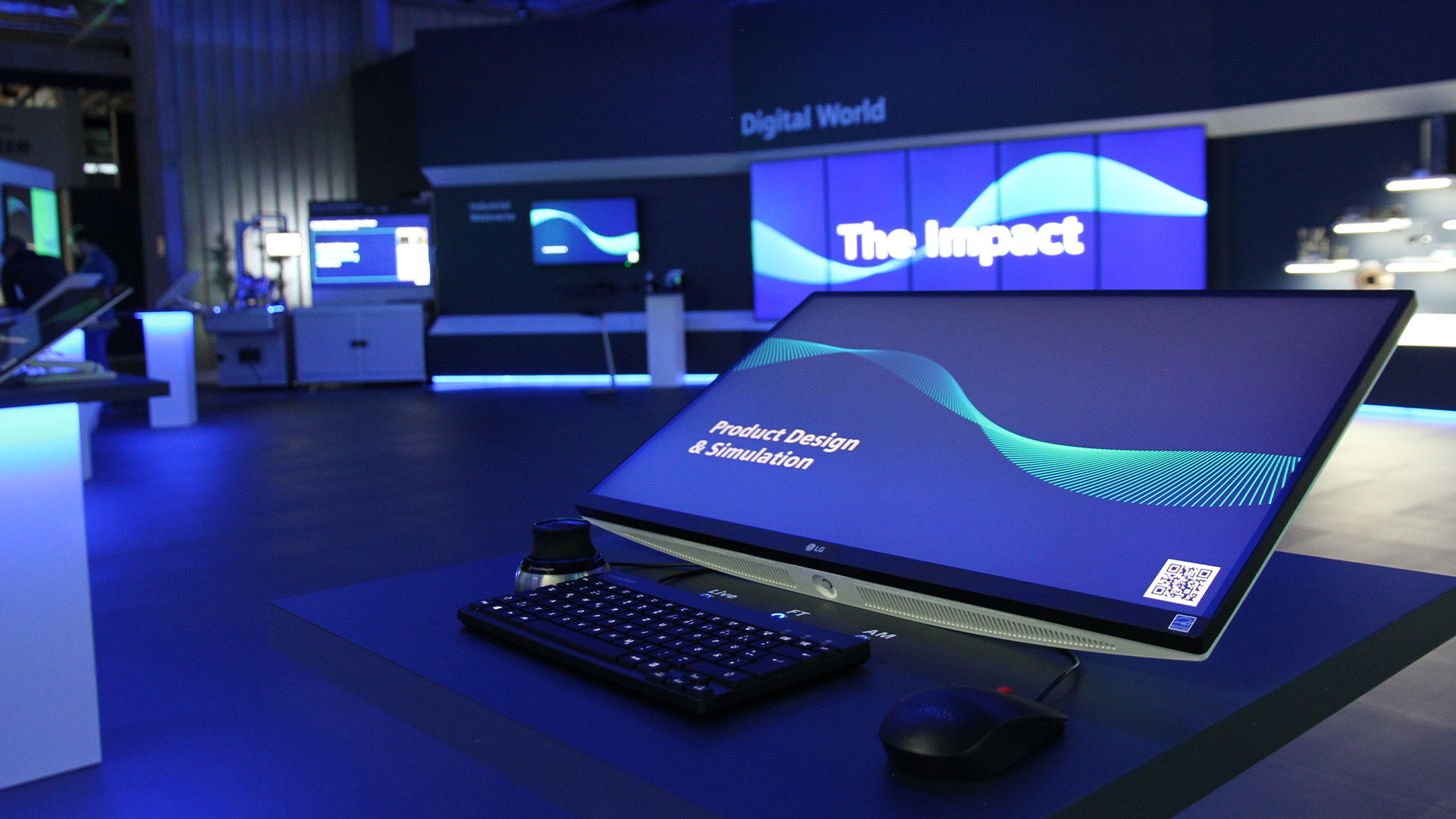 Ein Showroom mit Bildschirmen und Leuchtakzenten, im Vordergrund steht ein Bildschirm mit Maus und Tastatur