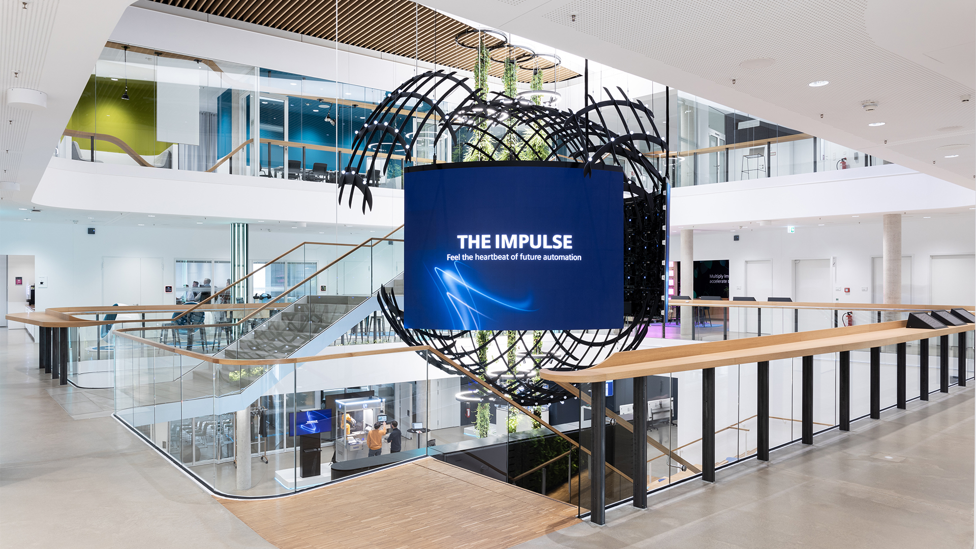 B12-Touch Showroom: Treppenhaus im Digital Experience Center mit großem Bildschirm, auf dem „The Impulse“ steht