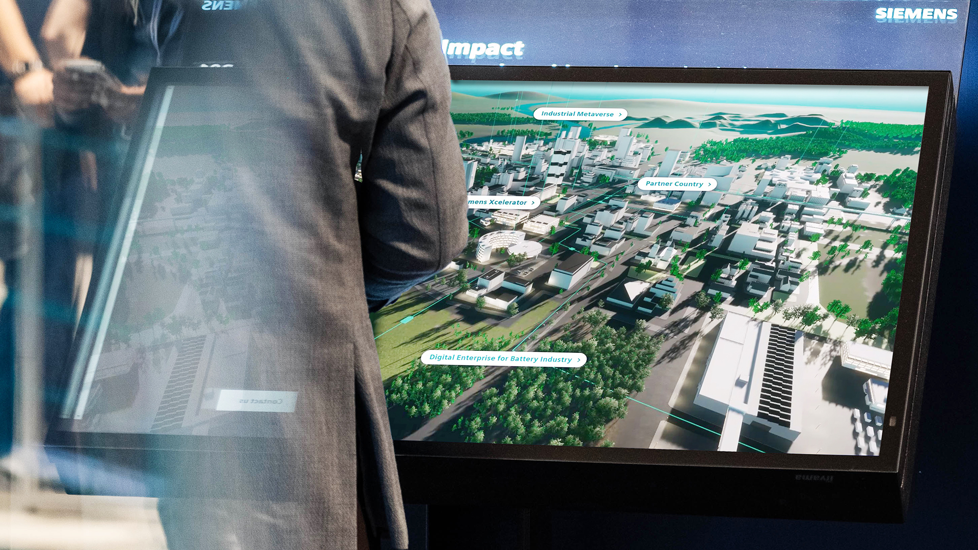 Mensch steht vor großem Bildschirm, auf dem eine virtuelle Stadt abgebildet ist – interaktive Vertriebspräsentationen
