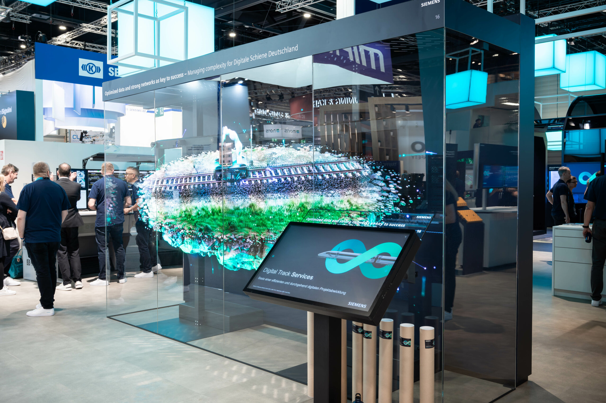 Digitales Exponat auf der Innotrans Messe mit Einsatz des B12 Headless CMS, im Hintergrund viele Messebesucher*innen